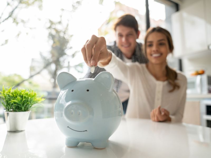 Couple adding money to piggy bank as their saving